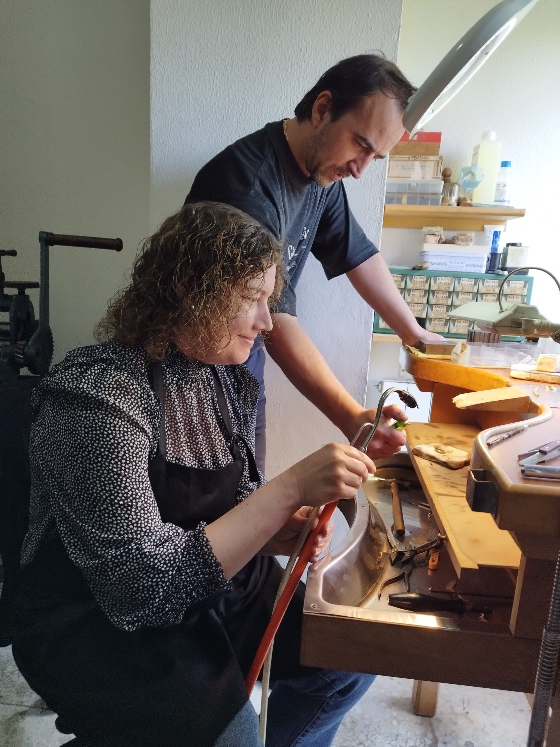 Rosa usando el soplete para soldar un anillo con Juanjo Artesano Joyero a su lado supervisando.
